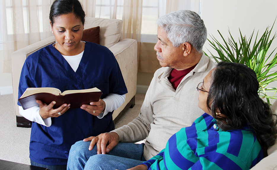 A health professional sits and interprets to help a non-English speaking couple.