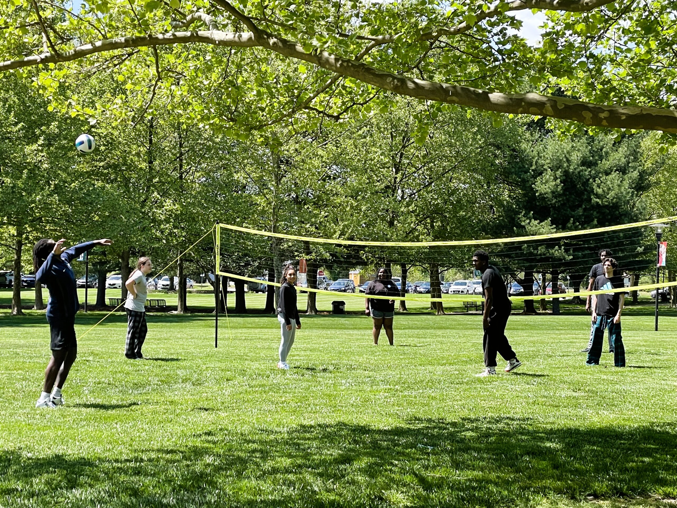 People playing volleyball in a grassy park, to promote welcome week tie dye and volleyball activities.