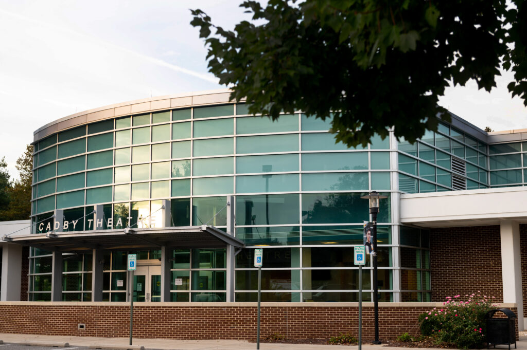 glass facade of the Cadby Theatre with the setting sun lighting the center section