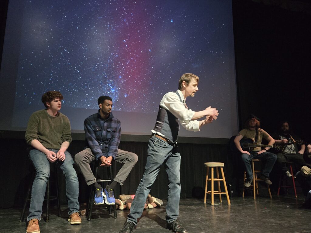 actors gathered on stage with a starry night backdrop
