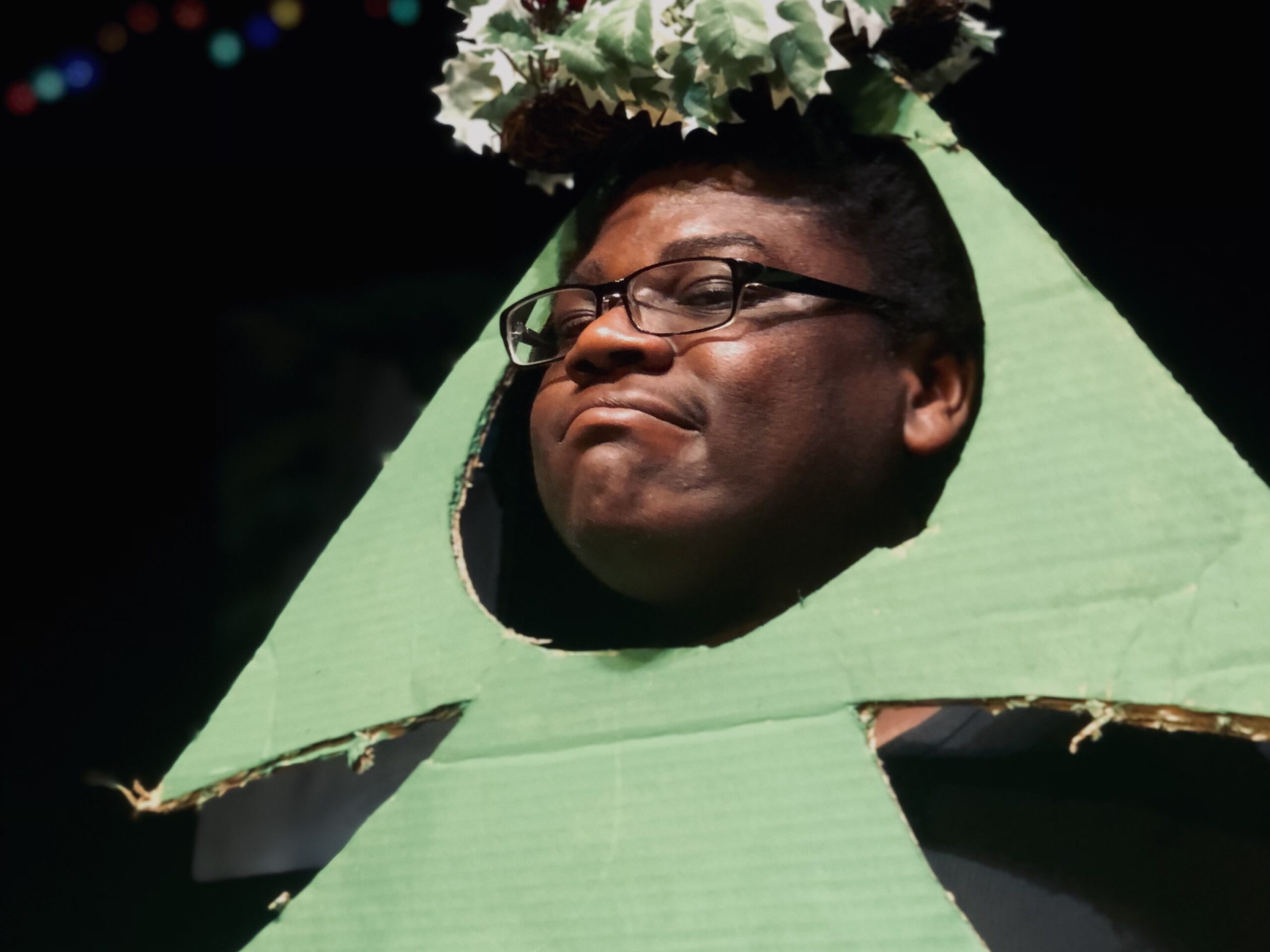 an actor wears a cut-out Christmas tree and garland
