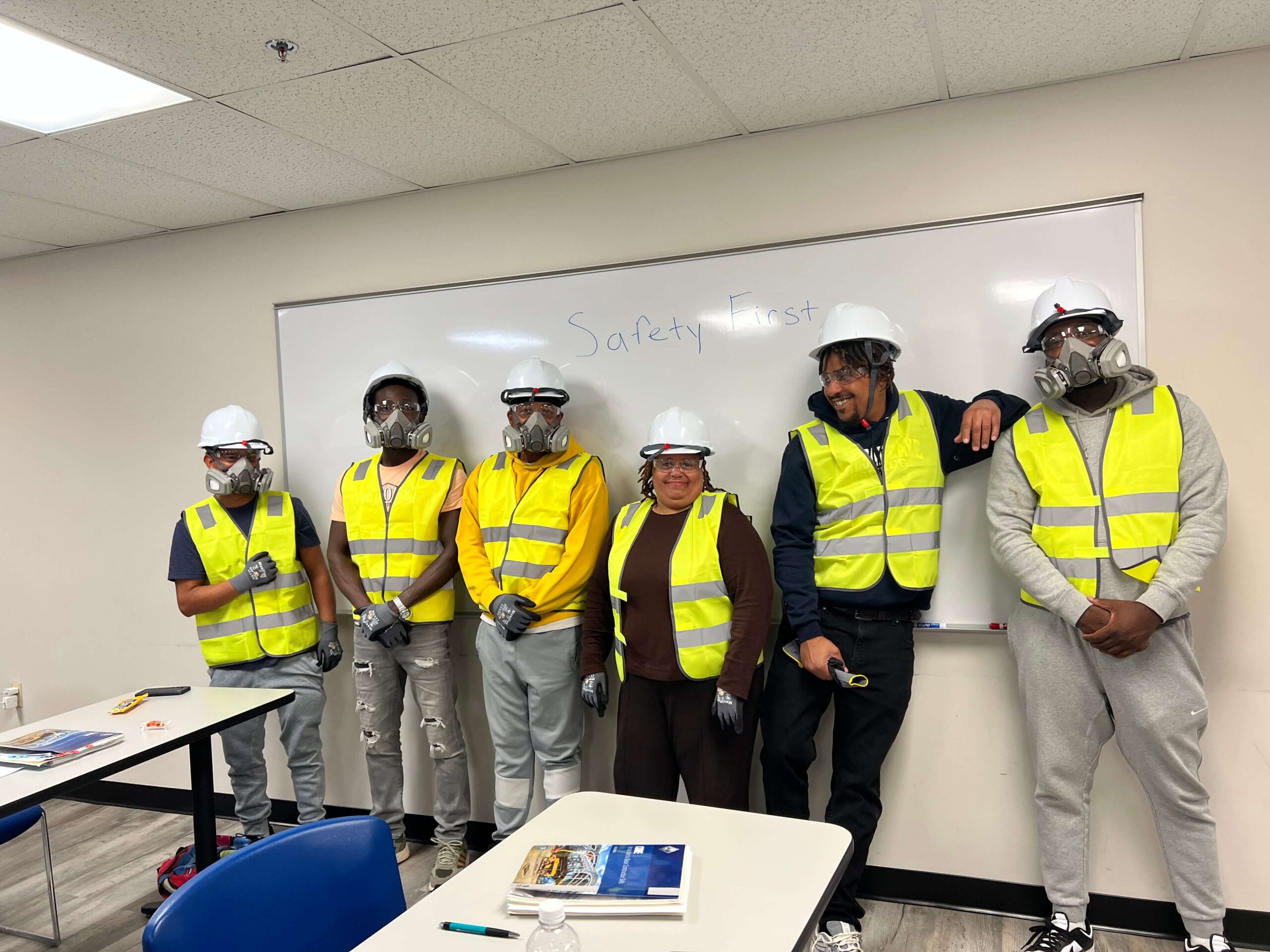 a group of students in safety gear standing against a whiteboard, smiling.