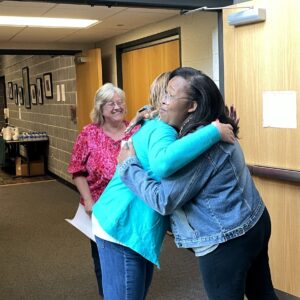 two attendees share a hug while a third one smiles at the greeting during a Project Right Steps Training Day