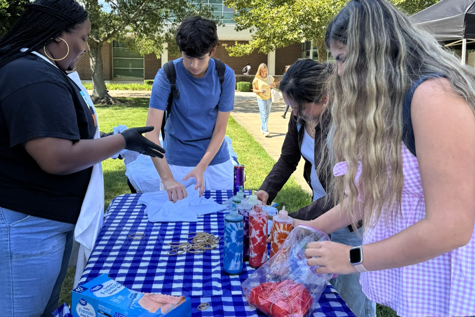Student Government Association member with other students in a welcome week tie dye activity